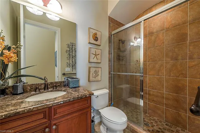a bathroom with a granite countertop sink a toilet a mirror and shower