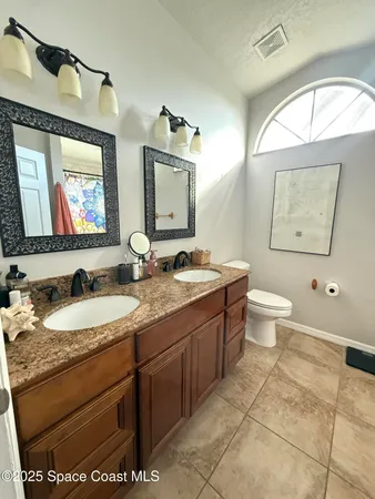a bathroom with a granite countertop toilet sink and mirror