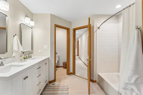 a bathroom with a double vanity sink a mirror and a bathtub
