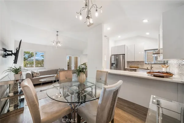 a dining room with wooden floor a chandelier a glass table and chairs