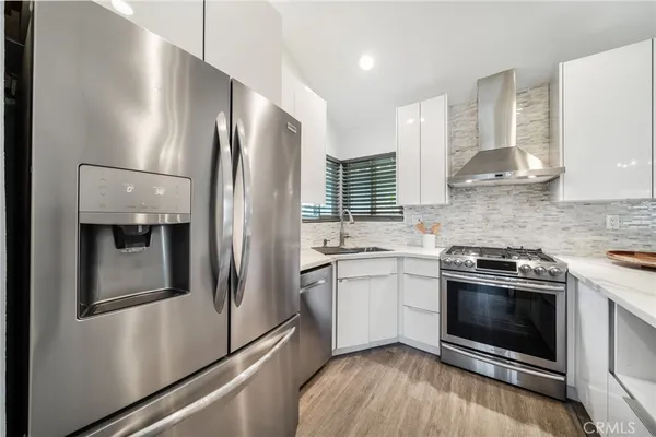 a kitchen with stainless steel appliances granite countertop a stove a refrigerator and a stove top oven