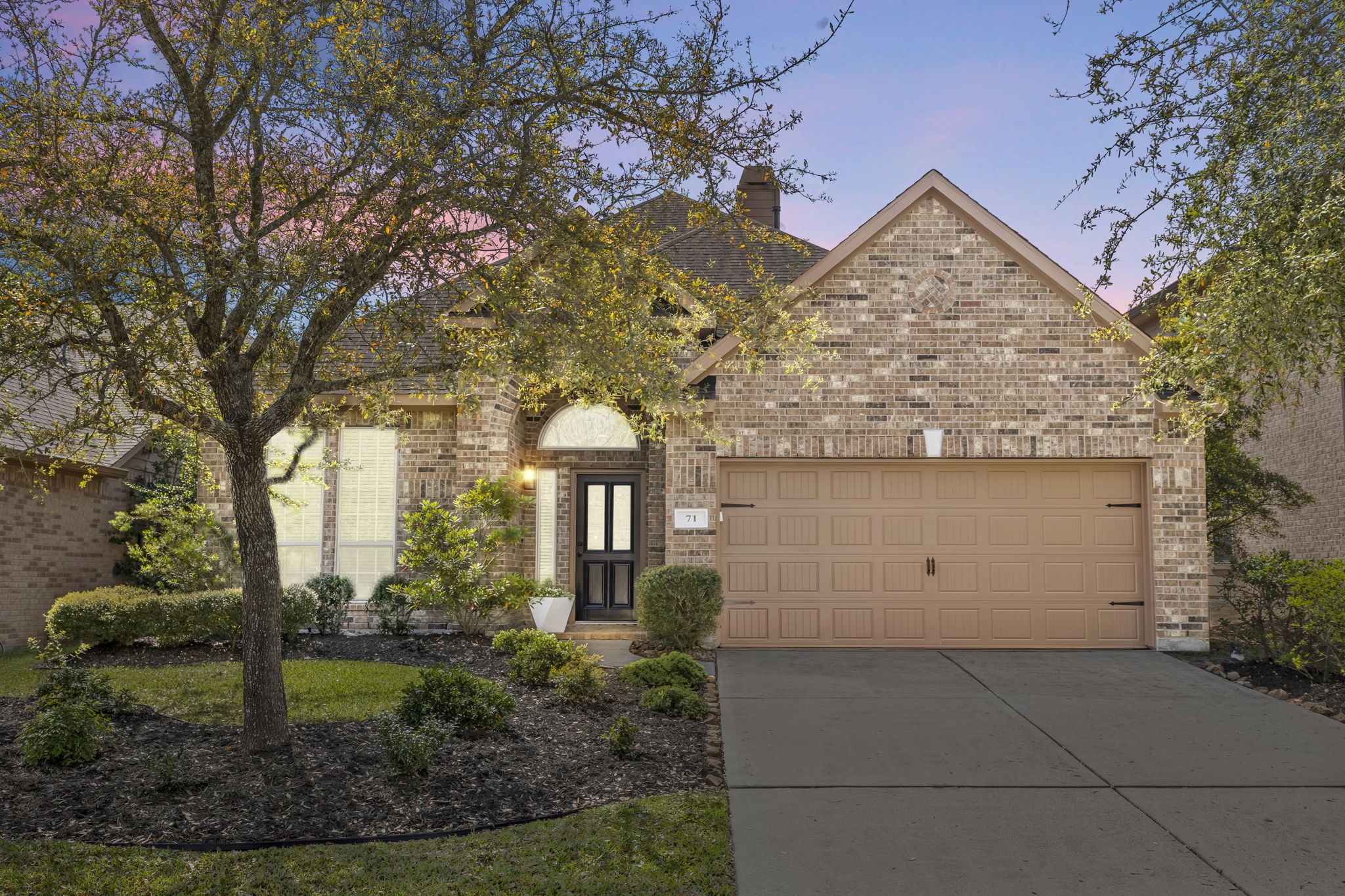 New listing with timeless brick facade, arched entry, and spacious two-car garage framed by mature trees.