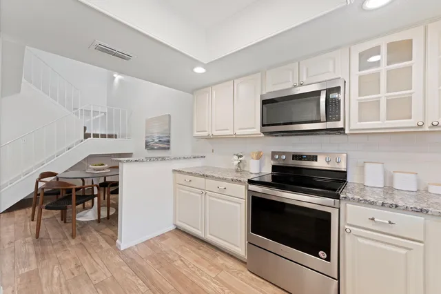 a kitchen with granite countertop cabinets stainless steel appliances a sink and a window