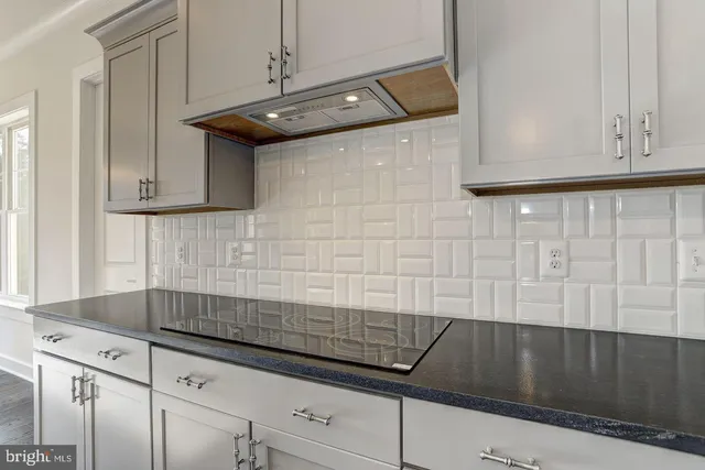 a kitchen with granite countertop white cabinets and black appliances