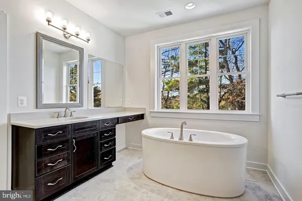 a bathroom with a tub a sink and a window