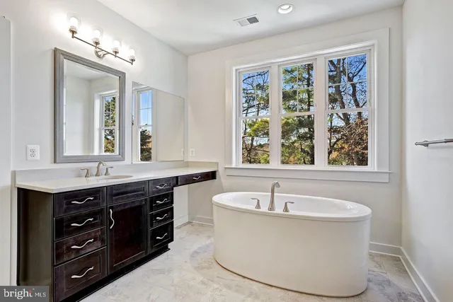 a bathroom with a tub a sink and a window