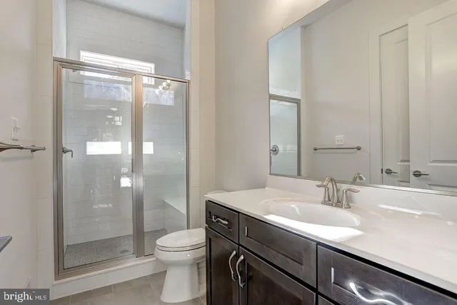 a bathroom with a shower sink vanity mirror and toilet