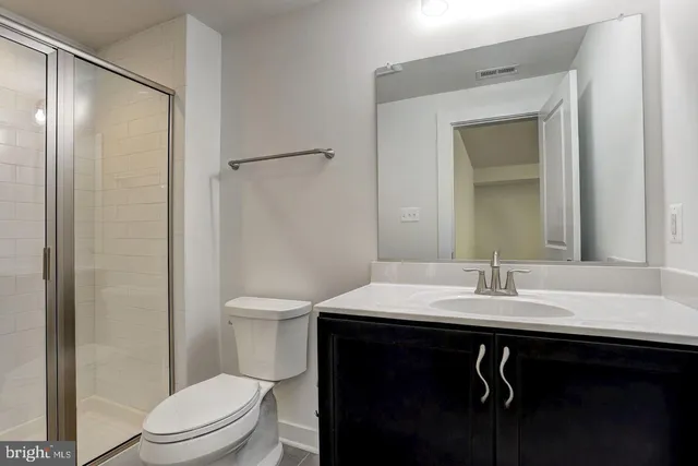 a bathroom with a sink a toilet a mirror and shower