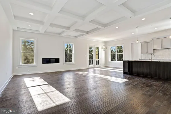 a view of an empty room with kitchen and window