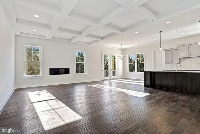 a view of an empty room with kitchen and window