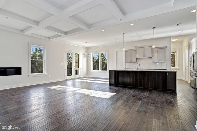 a living room with wooden floors and kitchen view