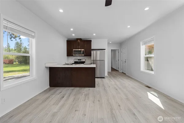 a large kitchen with stainless steel appliances granite countertop a large counter top a wooden floors and a large window