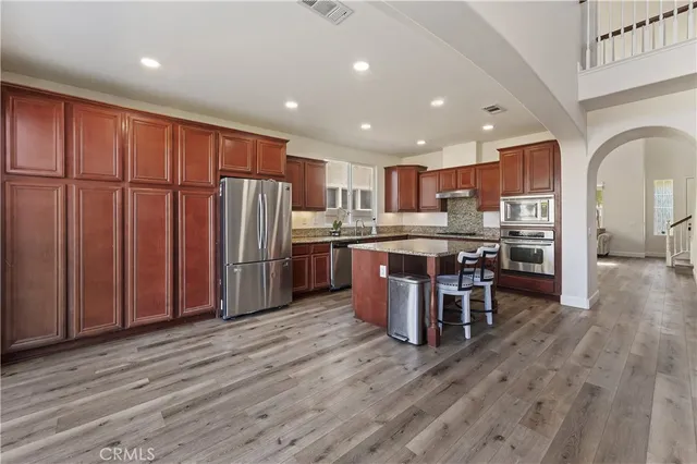 a kitchen with stainless steel appliances kitchen island granite countertop wooden floors and wooden cabinets