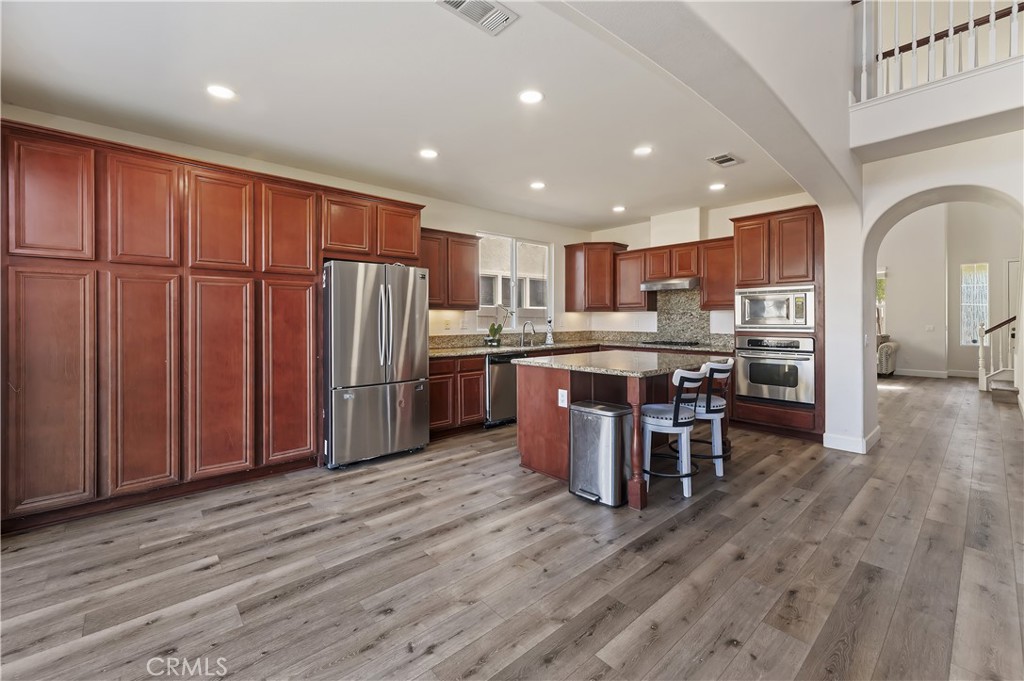 31244 Locust Court Temecula, CA 92592 - Photo 11 of 30 a kitchen with stainless steel appliances kitchen island granite countertop wooden floors and wooden cabinets