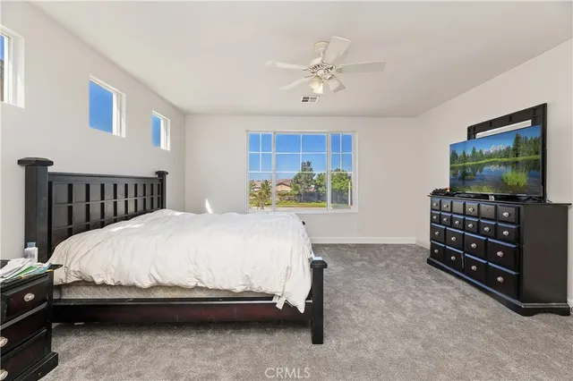 a bedroom with a bed and a flat tv screen on dresser