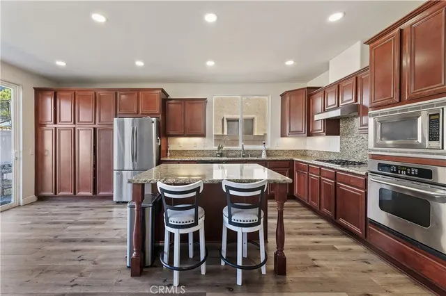 a kitchen with kitchen island granite countertop wooden cabinets and stainless steel appliances