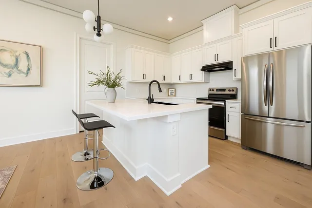 a kitchen with stainless steel appliances a sink a stove a refrigerator cabinets and a dining table