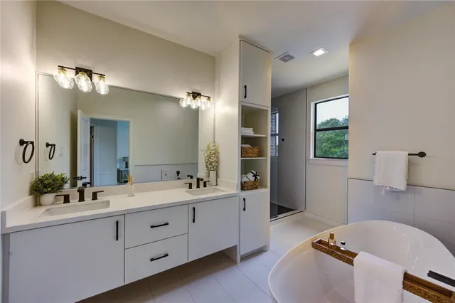 a spacious bathroom with a double vanity sink a mirror a bathtub and window