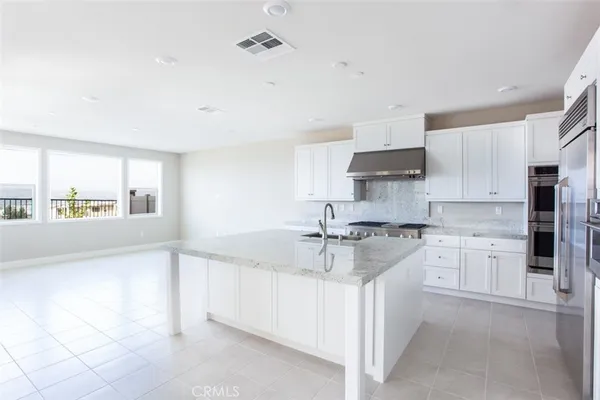 a kitchen with kitchen island granite countertop a sink stove and cabinets