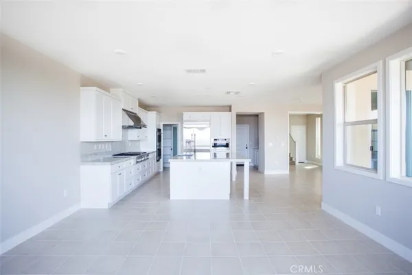 a view of open kitchen with white cabinets and wooden floor