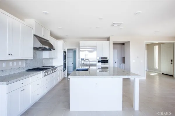 a large kitchen with stainless steel appliances granite countertop a lot of counter space and wooden floors