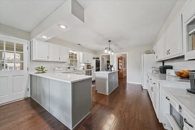 a large kitchen with stainless steel appliances granite countertop a lot of counter space and wooden floors