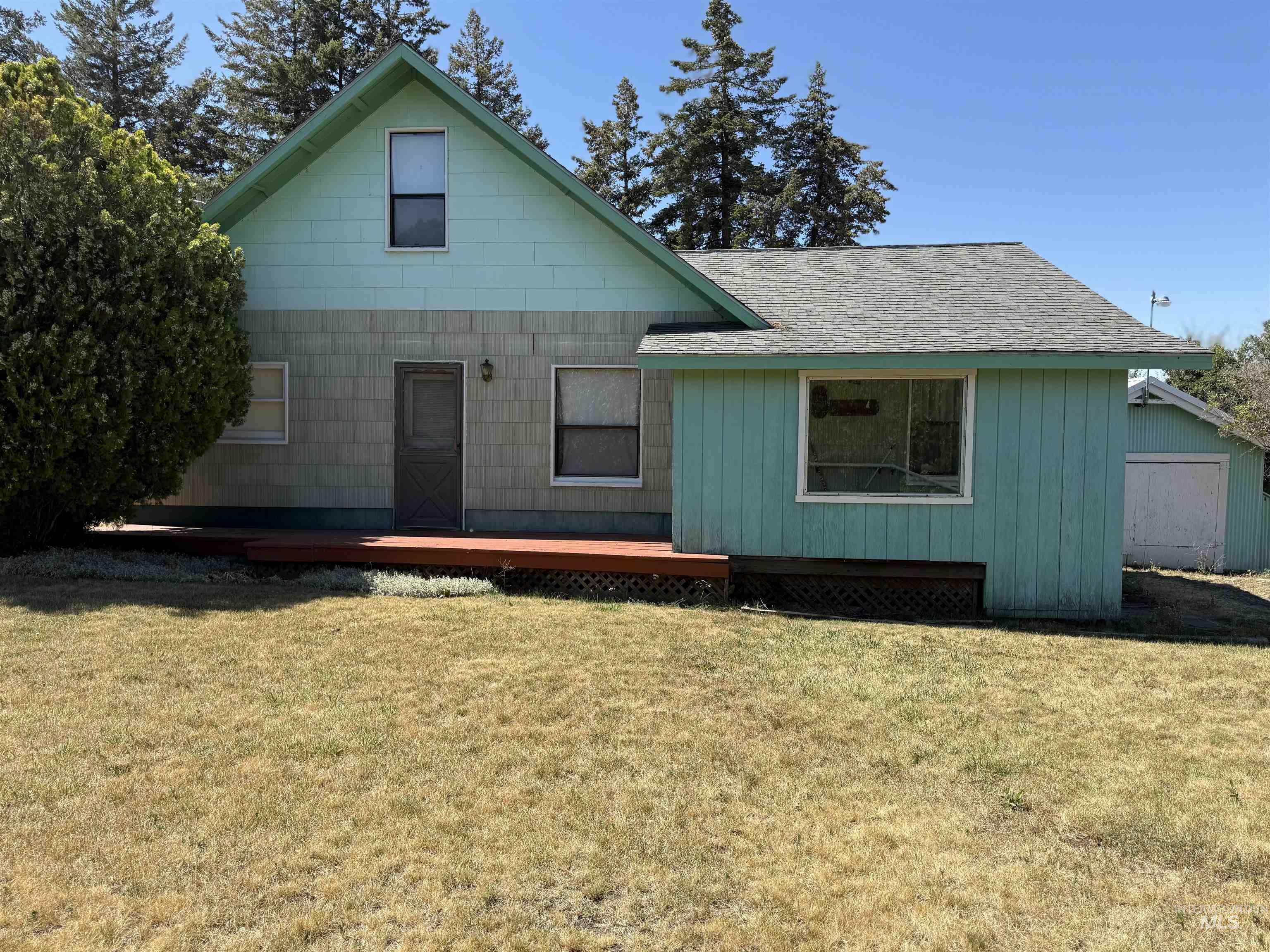 31678 Gifford Reubens Road Lenore, ID 83541 - Photo 1 of 1 Rear view of house with a lawn, a deck, and a shingled roof