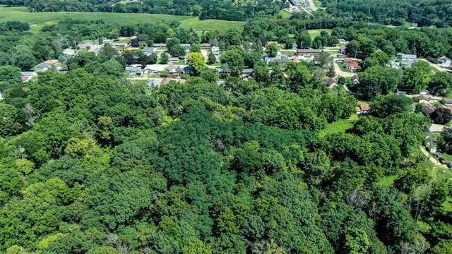 an aerial view of residential house with outdoor space and trees all around