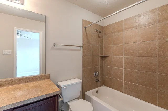 a bathroom with a granite countertop bathtub shower sink vanity and toilet