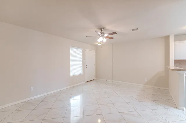en empty room with windows and chandelier fan