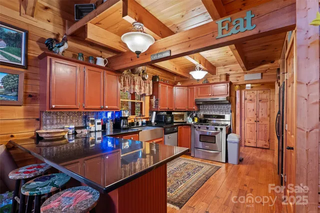 a open kitchen with stainless steel appliances granite countertop a stove a sink dishwasher and cabinets with wooden floor