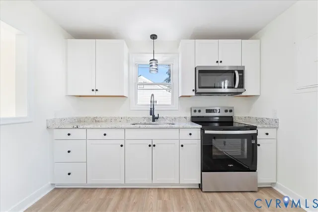 a kitchen with granite countertop white cabinets white stainless steel appliances and a sink