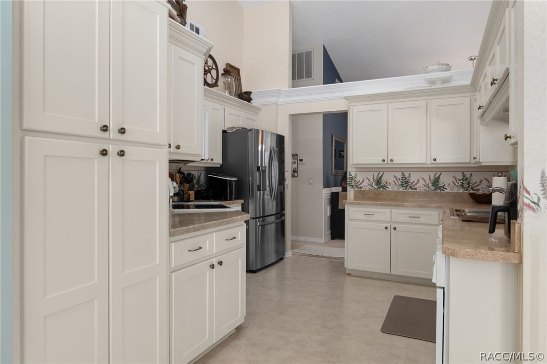 2460 West Pine Ridge Boulevard Beverly Hills, FL 34465 - Photo 12 of 47 a kitchen with white cabinets and stainless steel appliances