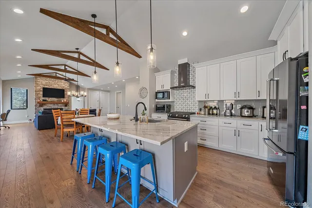 a kitchen with stainless steel appliances kitchen island granite countertop a table chairs sink and cabinets