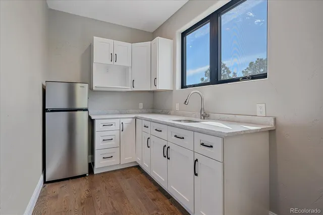 a kitchen with granite countertop white cabinets and refrigerator