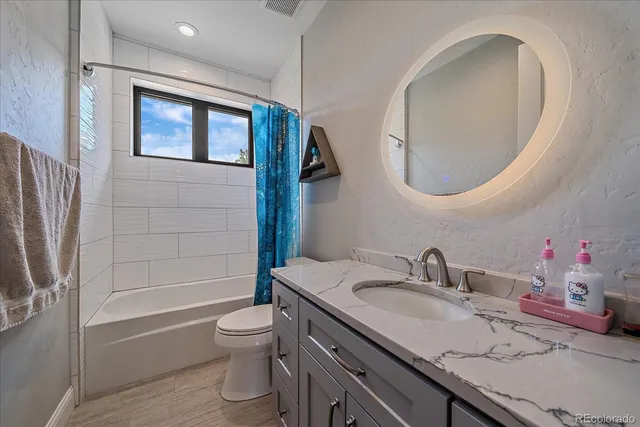 a bathroom with a granite countertop sink toilet and shower