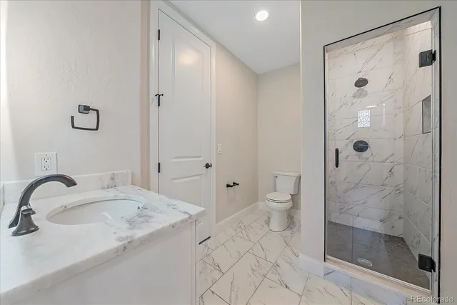 a bathroom with a granite countertop sink a toilet and shower