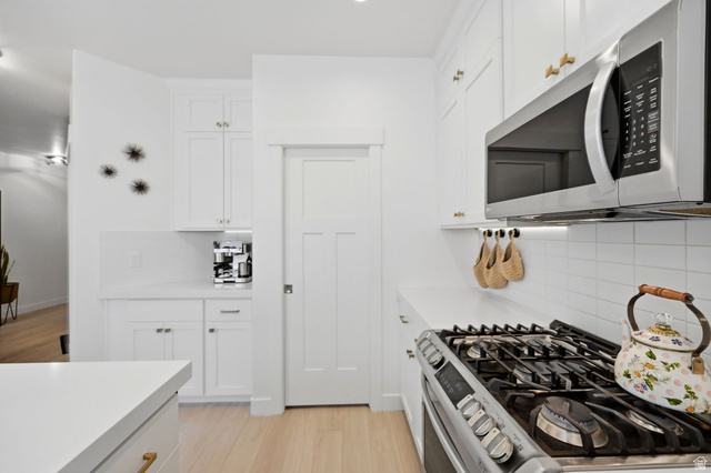 57 McCall Ln. Farmington, UT 84025 - Photo 8 of 36 Bright kitchen featuring white shaker cabinetry, stainless steel microwave, gas range with griddle, and white subway tile backsplash