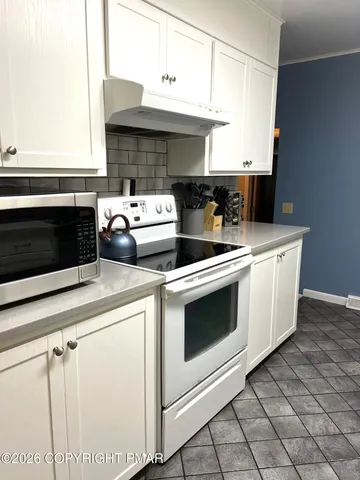 a kitchen with a stove and white cabinets