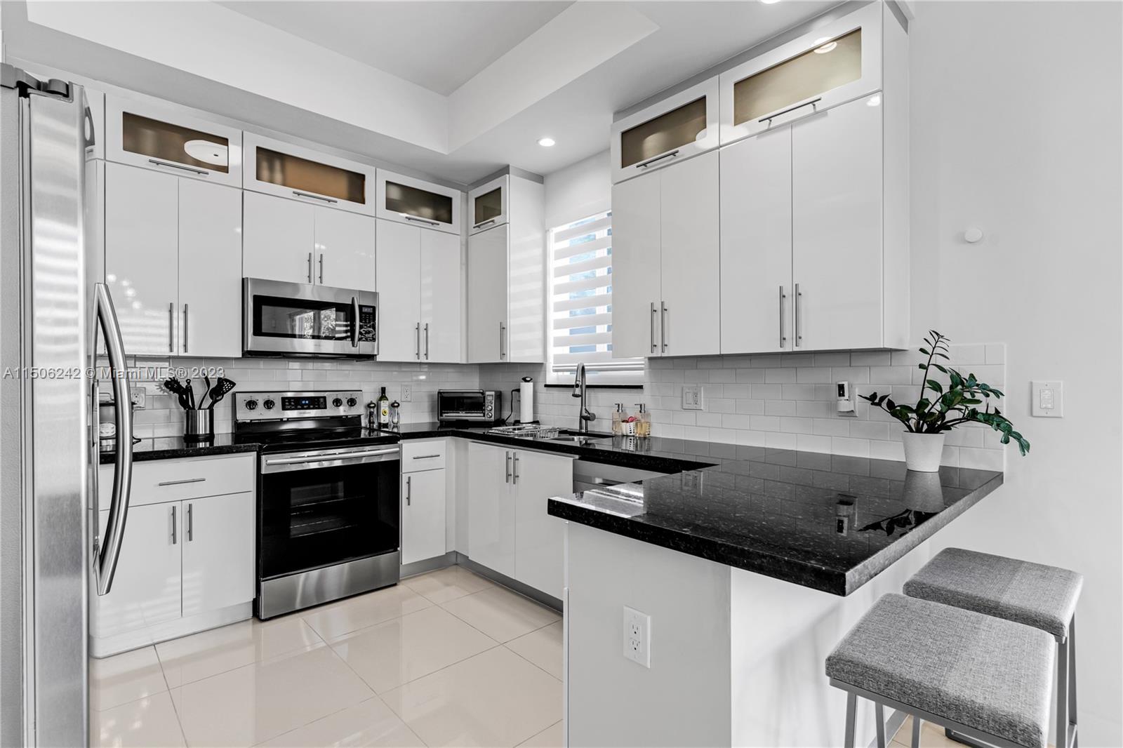 3916 Southwest 69th Avenue Miami, FL 33155 - Photo 2 of 7 a kitchen with granite countertop a sink a stove top oven and white cabinets