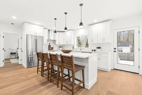 a kitchen with stainless steel appliances kitchen island granite countertop a dining table chairs and white cabinets