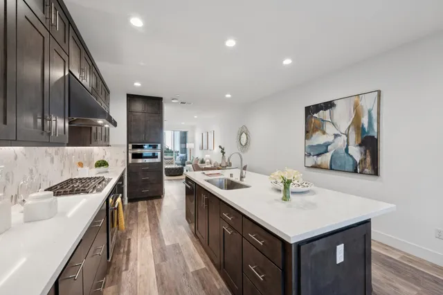 a kitchen with stainless steel appliances a sink stove cabinets and wooden floor