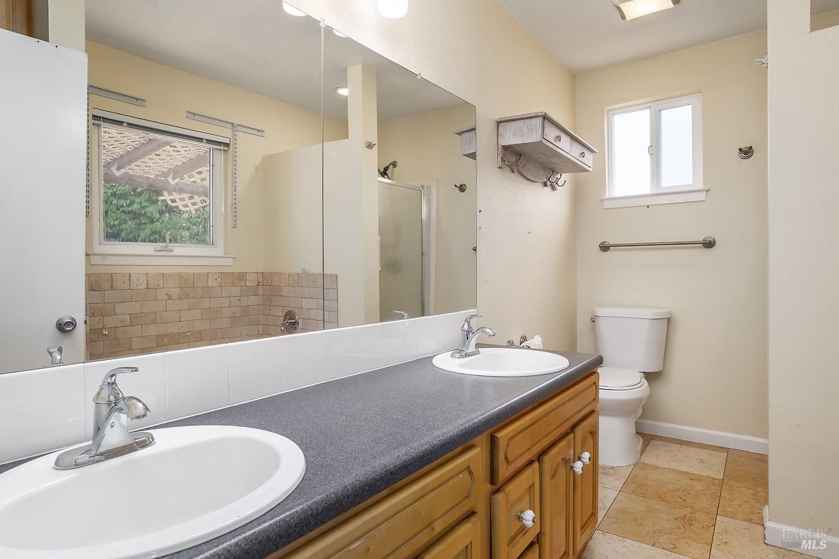 1135 4th Street Novato, CA 94945 - Photo 13 of 47 Primary suite bathroom with stone floors and double sinks. There is a stall shower and a separate tub, plus a linen cabinet.