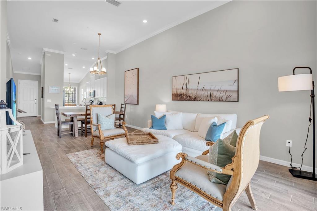 11761 Venetian Lagoon Drive, Unit 204 Fort Myers, FL 33913 - Photo 12 of 46 Living area featuring wood finish floors, baseboards, a chandelier, and crown molding