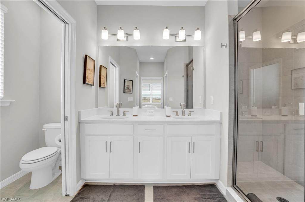 11761 Venetian Lagoon Drive, Unit 204 Fort Myers, FL 33913 - Photo 18 of 46 Full bathroom with double vanity, a shower stall, toilet, and a sink