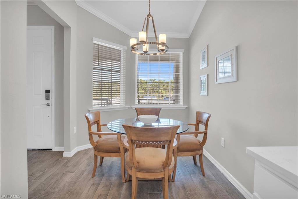 11761 Venetian Lagoon Drive, Unit 204 Fort Myers, FL 33913 - Photo 2 of 46 Dining area with wood finish floors, baseboards, an inviting chandelier, and ornamental molding