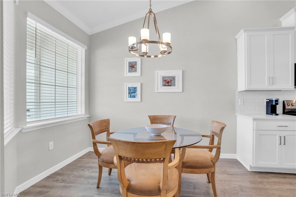11761 Venetian Lagoon Drive, Unit 204 Fort Myers, FL 33913 - Photo 3 of 46 Dining space featuring light wood-style floors, baseboards, a notable chandelier, and ornamental molding