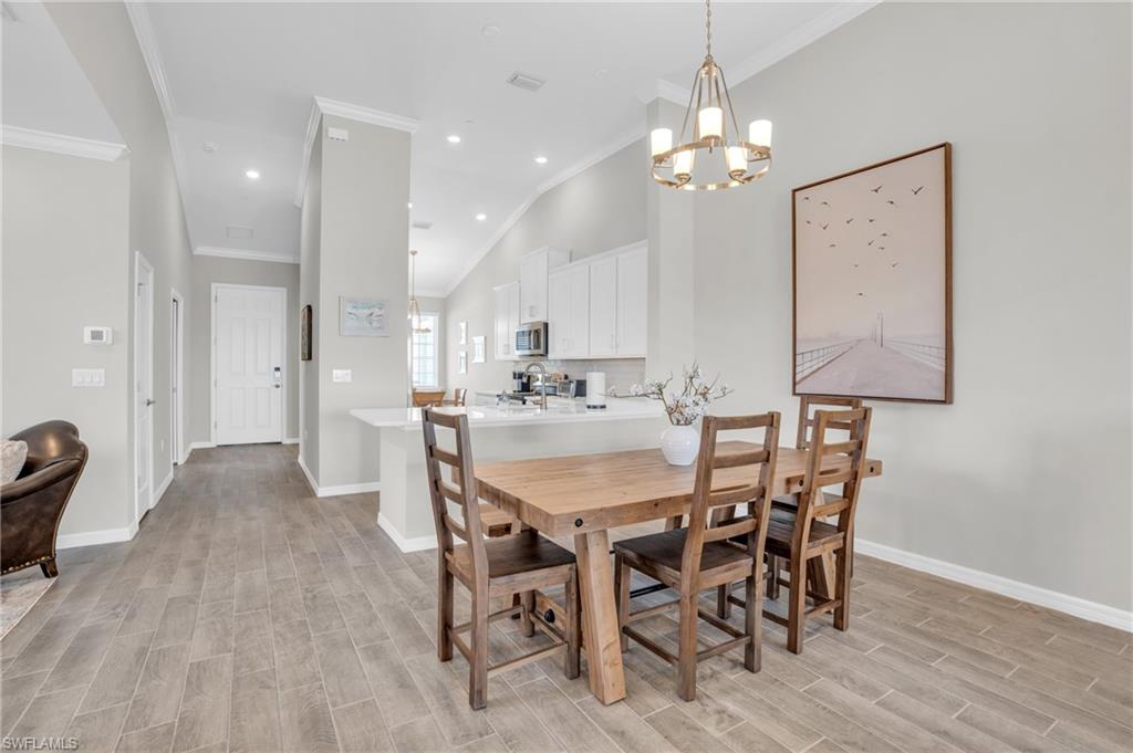 11761 Venetian Lagoon Drive, Unit 204 Fort Myers, FL 33913 - Photo 8 of 46 Dining space featuring recessed lighting, crown molding, baseboards, a chandelier, and wood tiled floor