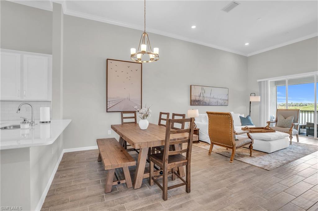 11761 Venetian Lagoon Drive, Unit 204 Fort Myers, FL 33913 - Photo 9 of 46 Dining space with wood tiled floor, ornamental molding, visible vents, and a chandelier
