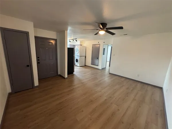 an empty room with wooden floor and a ceiling fan